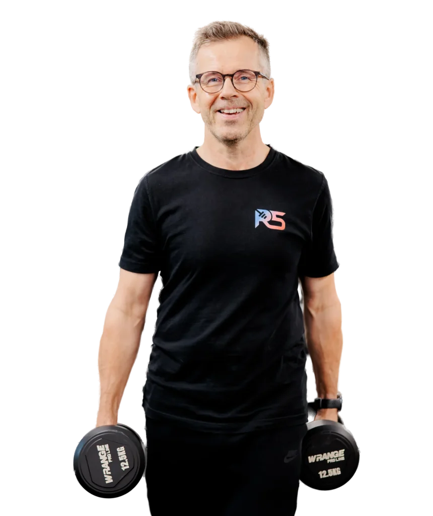 Personal trainer Jerry Ketola hymyilee käsipainot käsissään