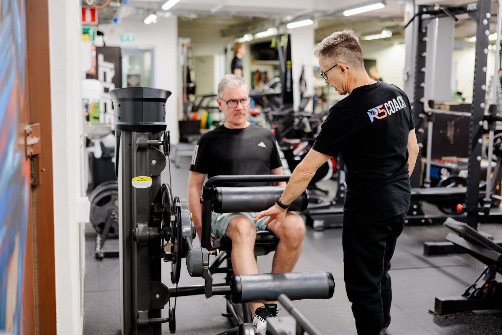Personal trainer Jerry Ketola guiding a client on a leg extension machine at the gym