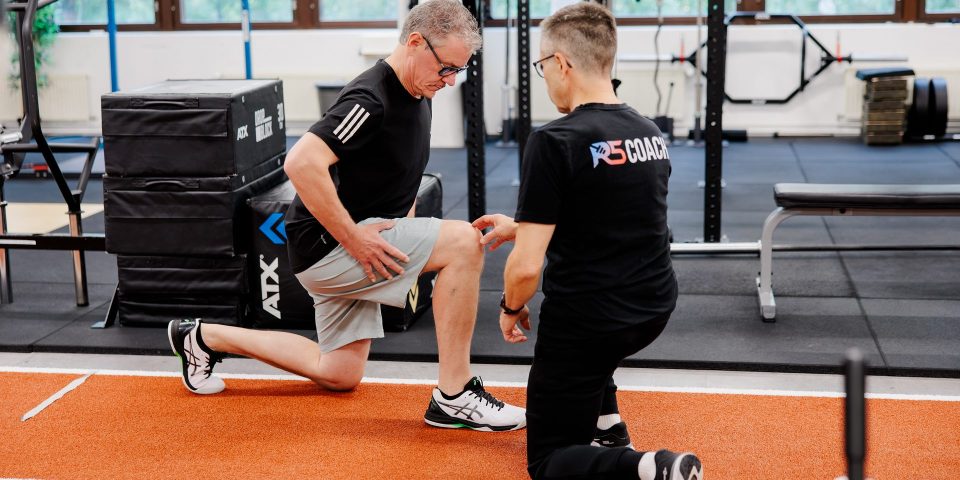 Personal trainer Jerry Ketola arvioi asiakkaan polven asentoa askelkyykyssä R5-kuntosalilla